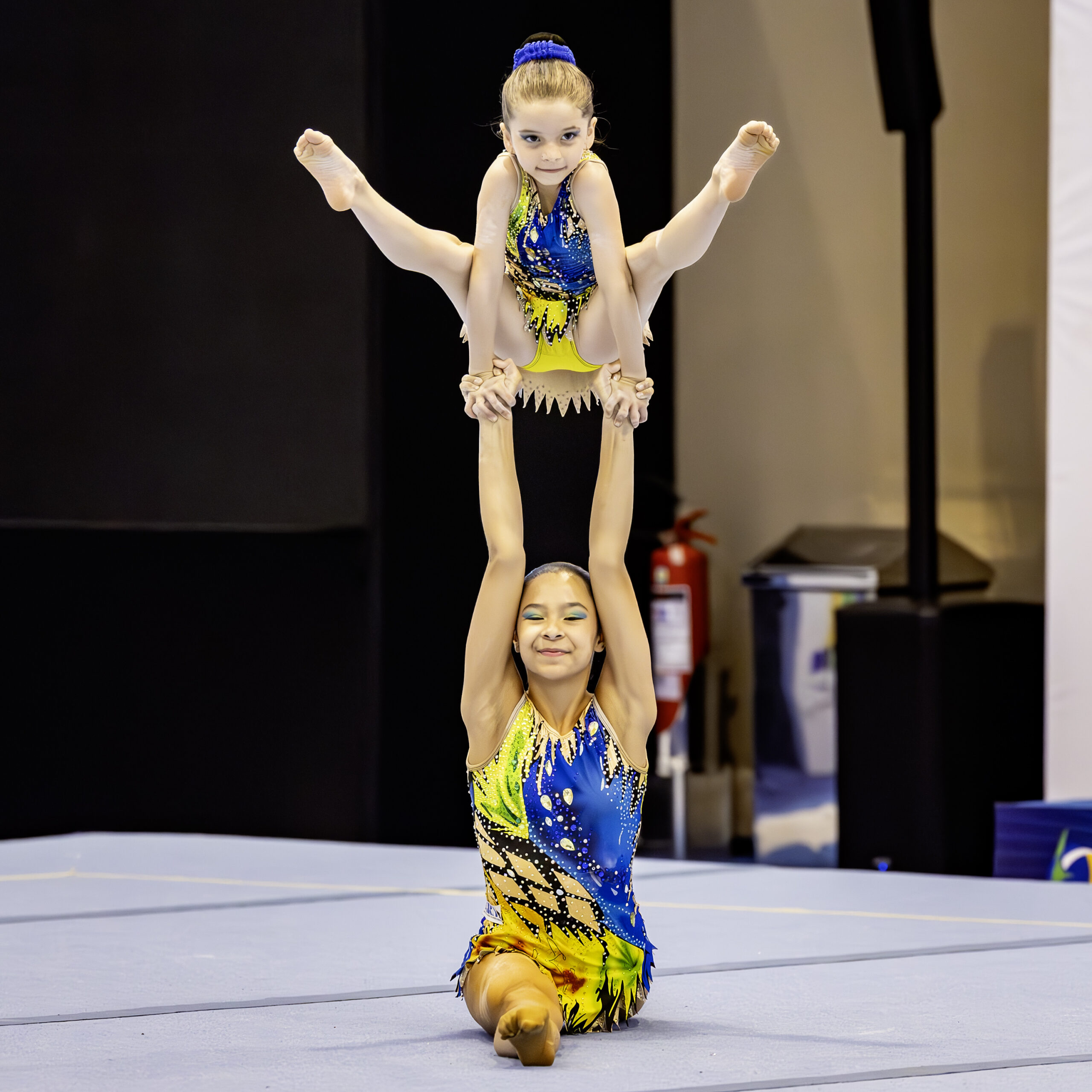 Duo acrob√°tico de gin√°stica em apresenta√ß√£o com fundo preto