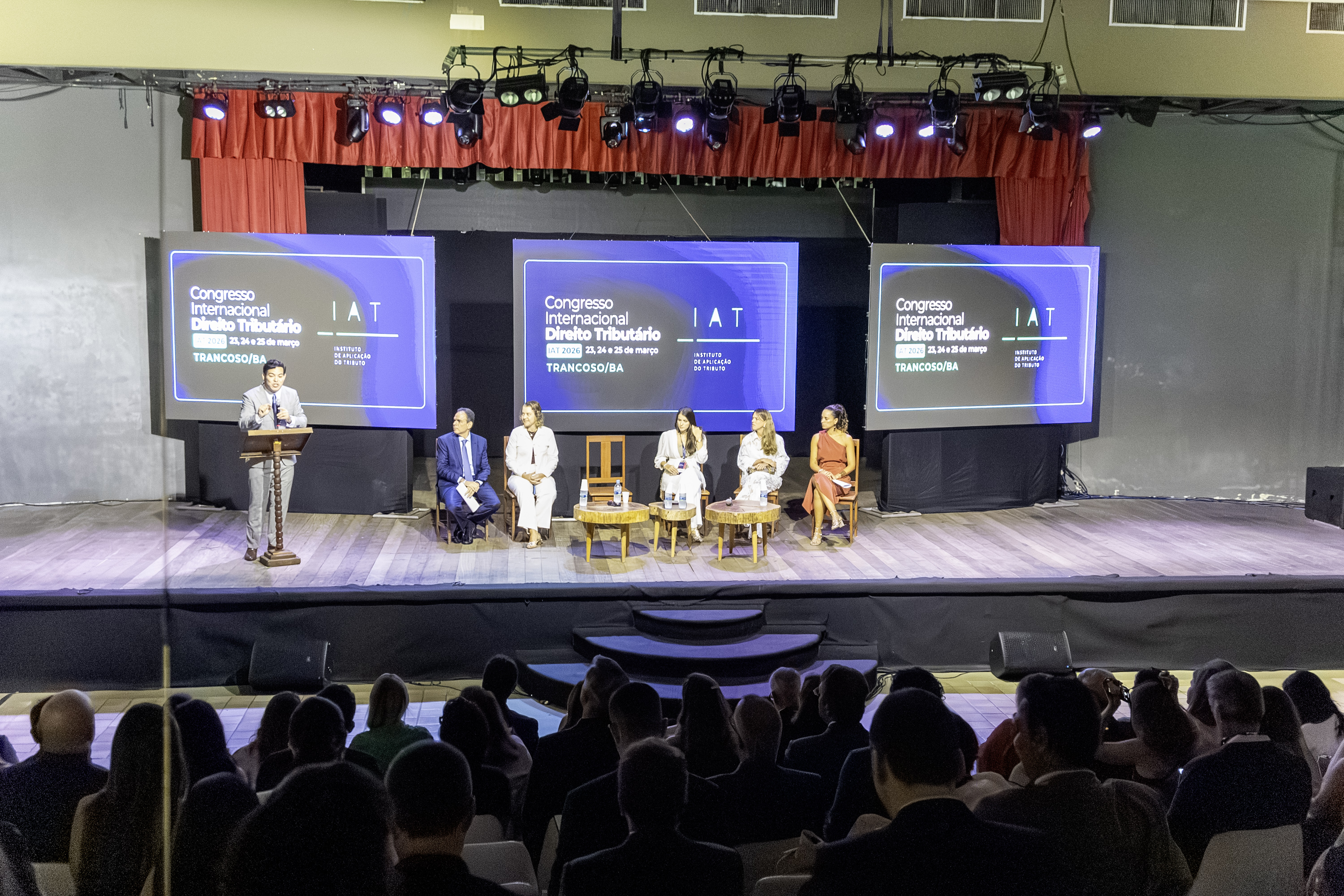 Congresso internacional com cortina vermelha e plateia