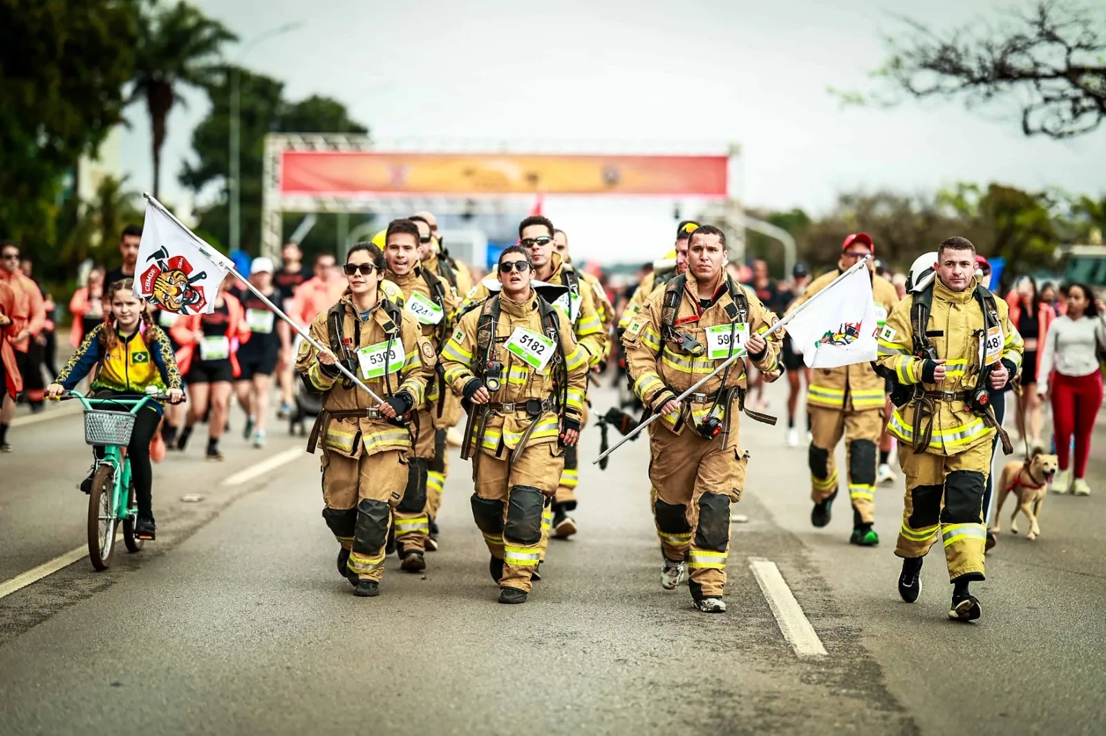 Tropa de bombeiros em traje completo marchando com bandeiras