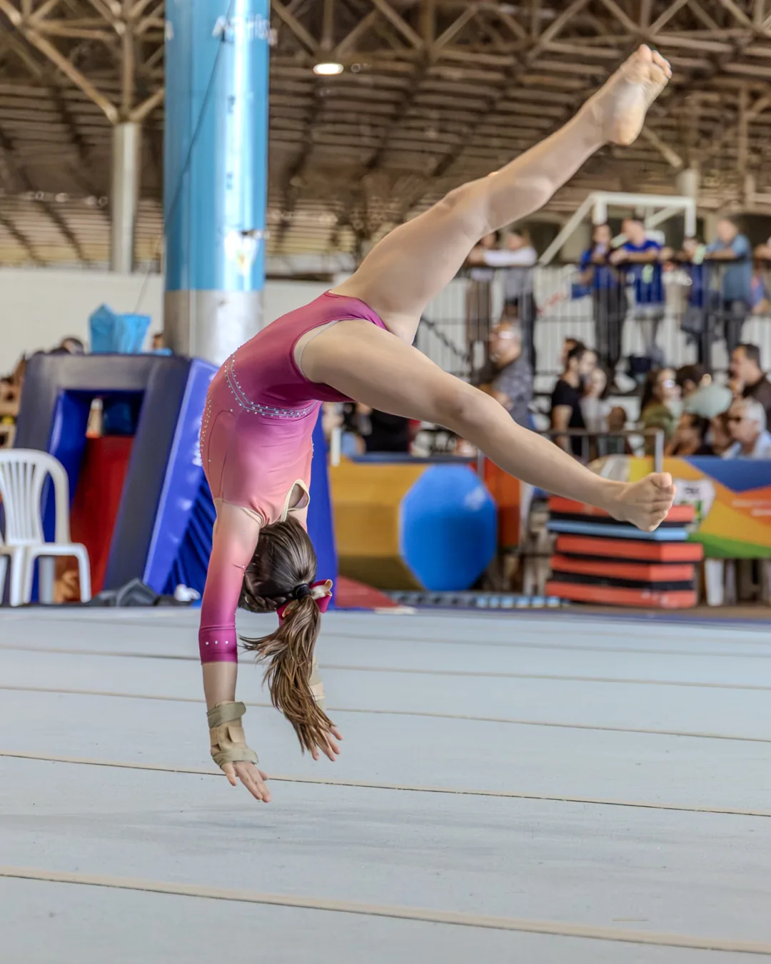 Ginasta de costas arqueadas em elemento acrobático no solo